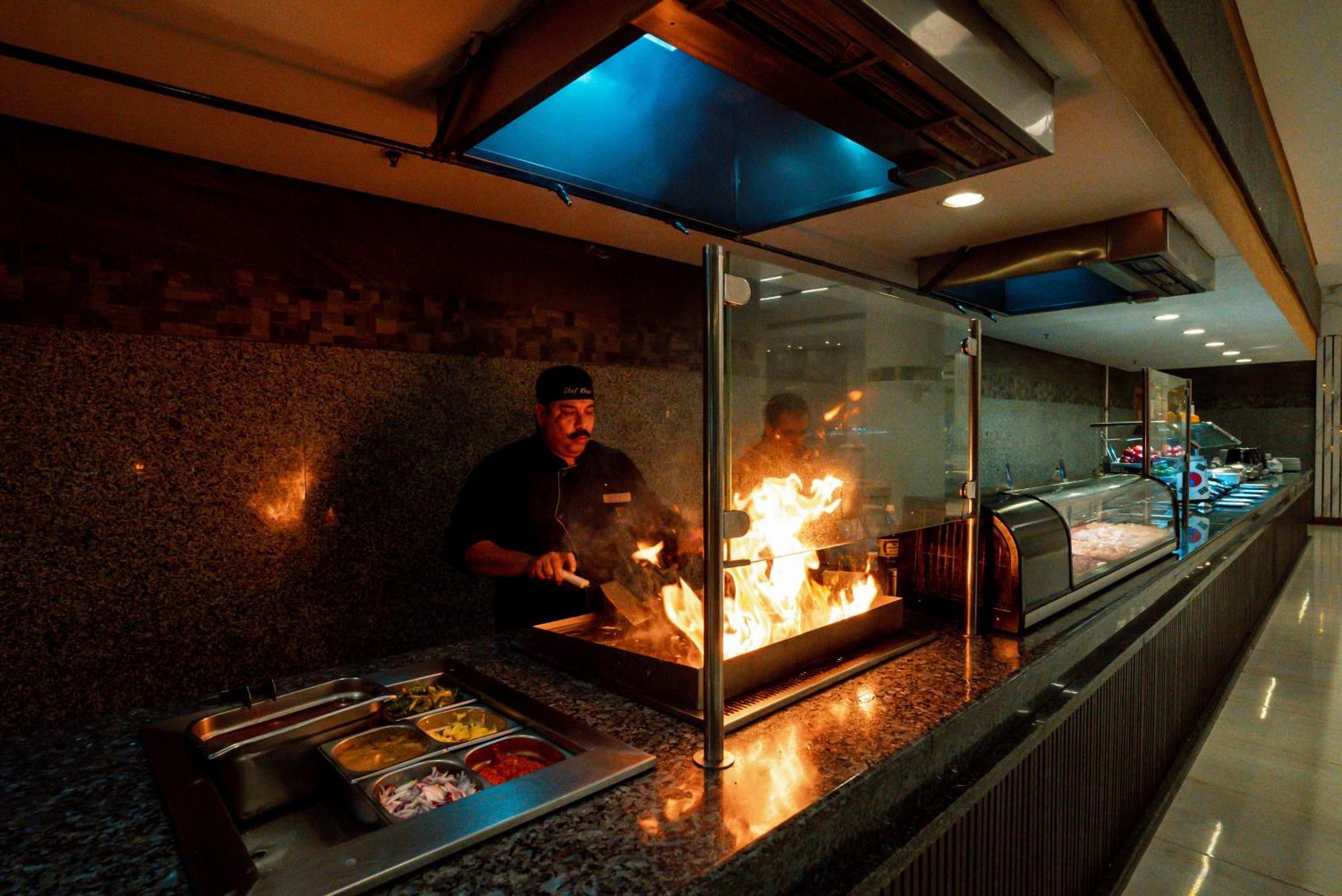 The V Luxury Resort Sahl Hasheesh Hurghada Exterior photo A chef cooking with a flaming torch