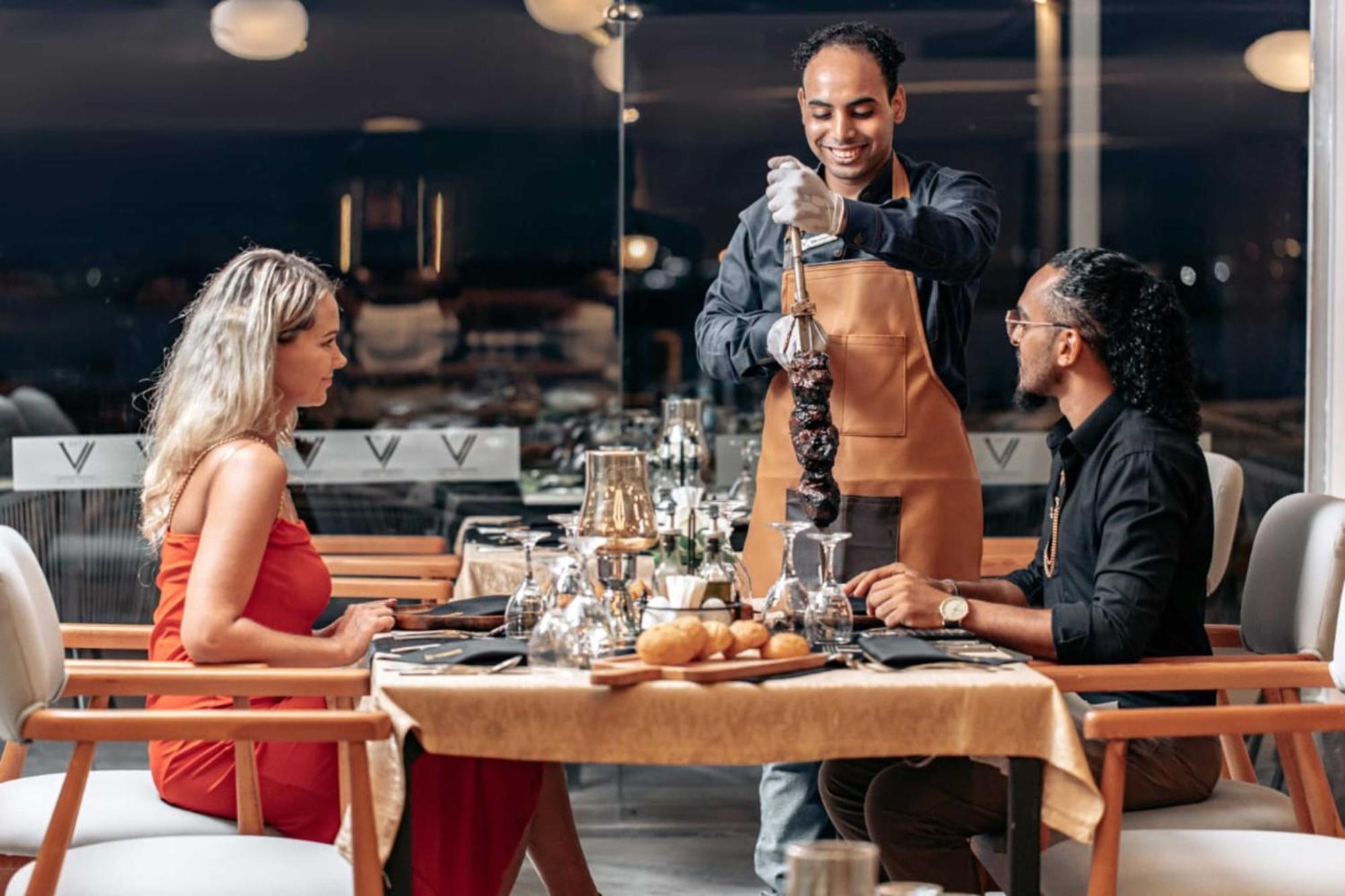 The V Luxury Resort Sahl Hasheesh Hurghada Exterior photo A waiter serving a couple at a restaurant